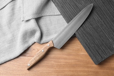 Photo of Flat lay composition with sharp chef's knife and board on wooden background
