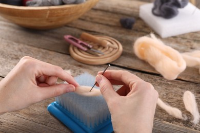 Photo of Woman felting from wool at wooden table, closeup