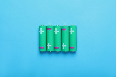 Photo of New AA size batteries on light blue background, flat lay