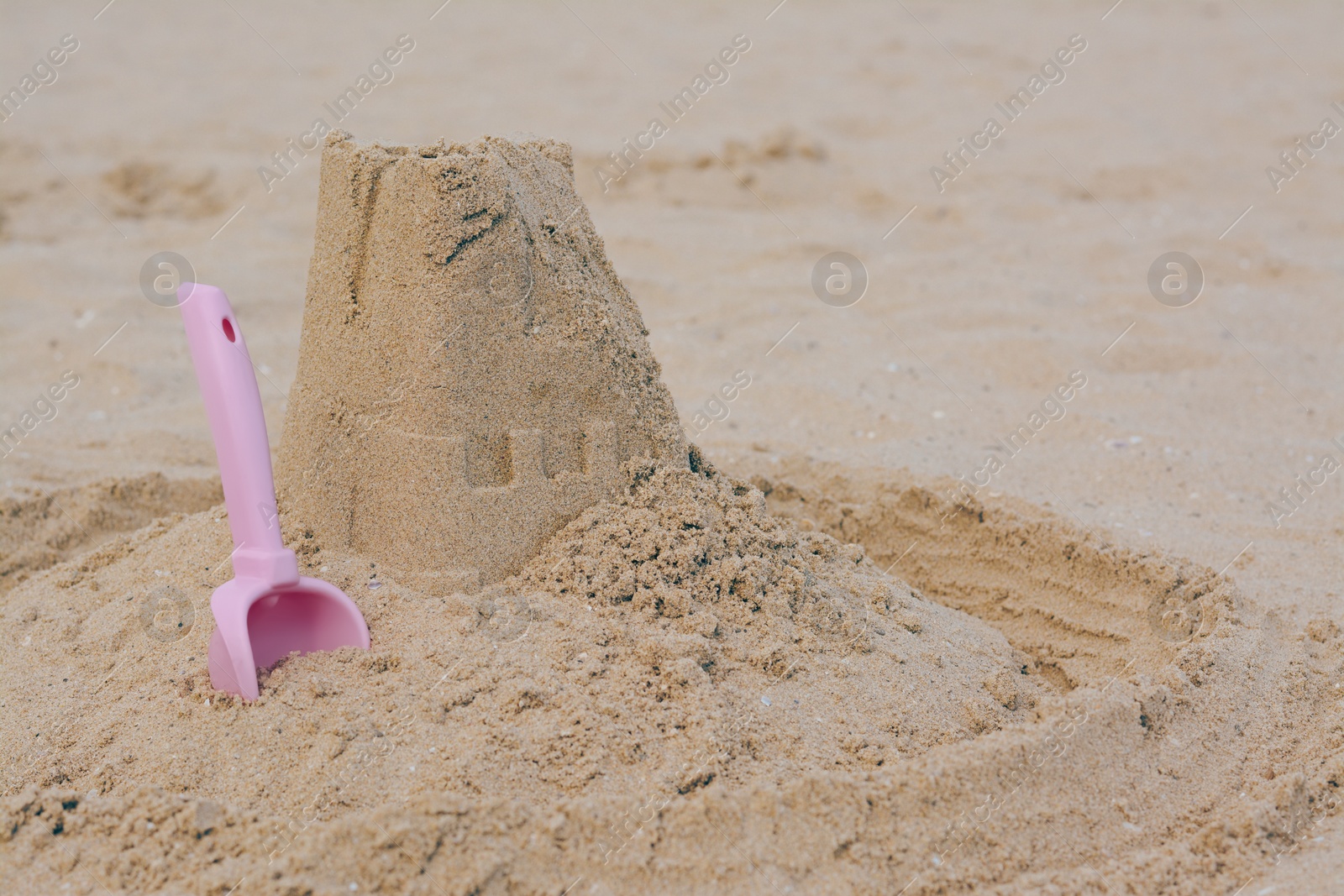 Photo of Beautiful sand castle and plastic toy on beach, space for text