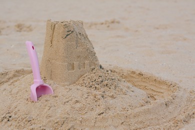 Photo of Beautiful sand castle and plastic toy on beach, space for text