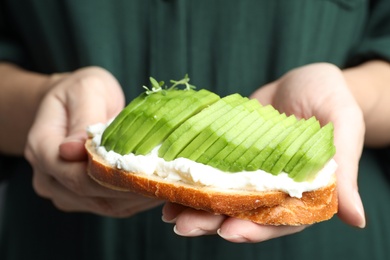 Photo of Woman holding tasty sandwich with avocado, closeup