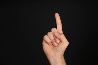 Photo of Man pointing at something on black background, closeup. Finger gesture