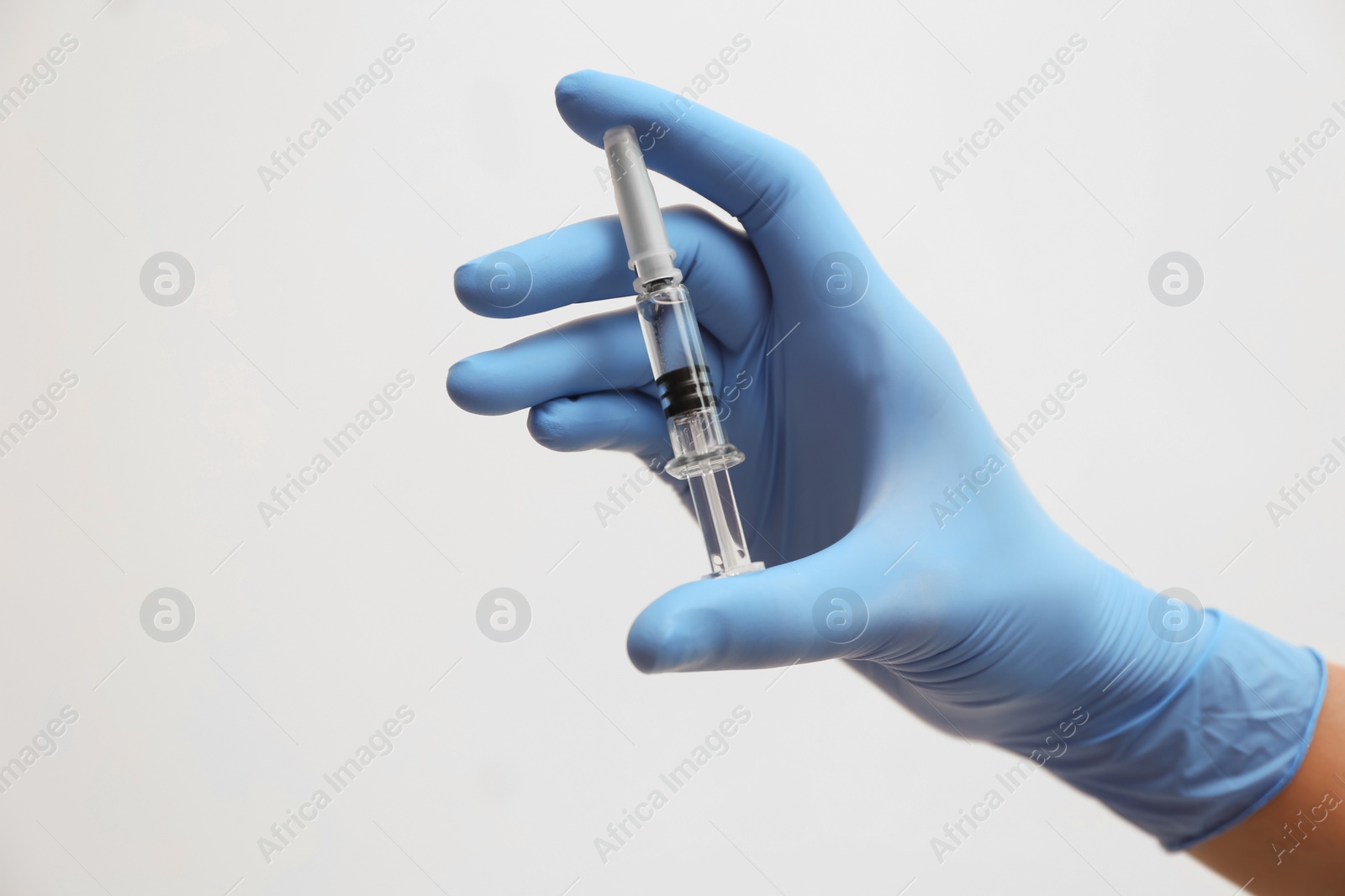 Photo of Doctor holding syringe with COVID-19 vaccine on light background, closeup