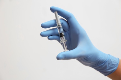 Photo of Doctor holding syringe with COVID-19 vaccine on light background, closeup