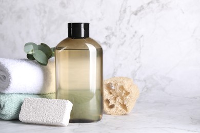 Photo of Shampoo bottle, loofah, folded towels and pumice on white marble table, space for text