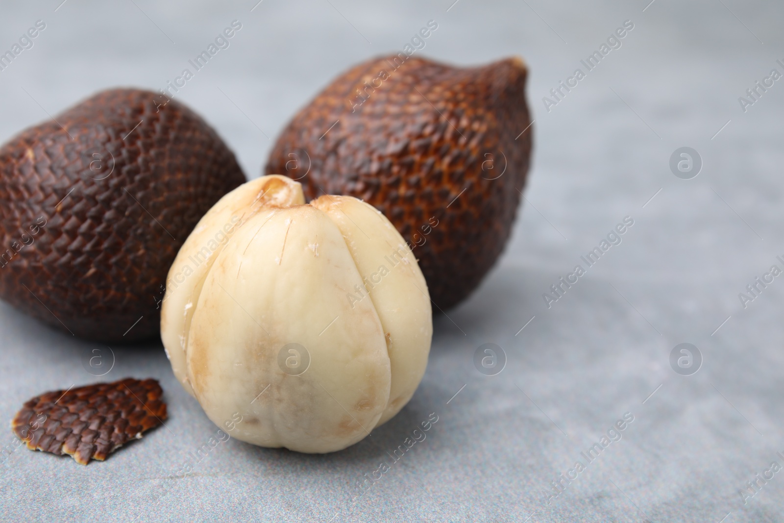 Photo of Fresh salak fruits on light grey table, closeup. Space for text