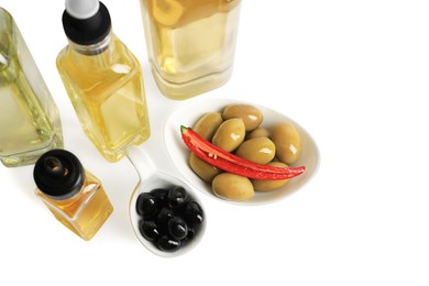 Bottles of different cooking oils and olives on white background, above view