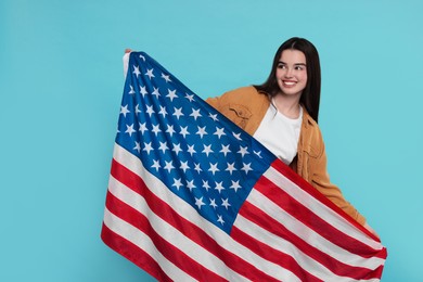 4th of July - Independence Day of USA. Happy girl with American flag on light blue background