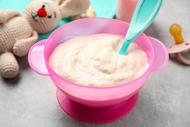 Photo of Healthy baby food in bowl on grey table, closeup