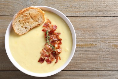 Tasty potato soup with bacon and crouton in bowl on wooden table, top view. Space for text