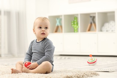 Photo of Children toys. Cute little boy playing with red ball on rug at home, space for text