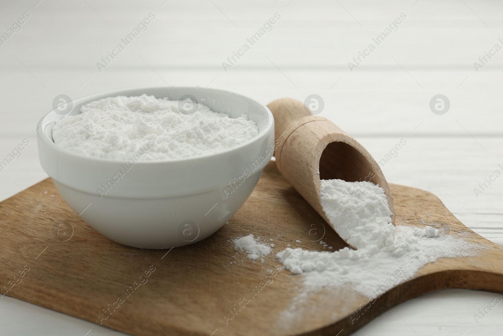 Photo of Baking powder in bowl and scoop on white wooden table