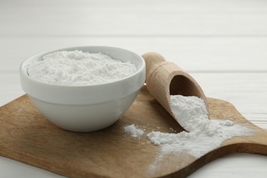 Baking powder in bowl and scoop on white wooden table