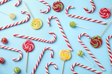 Flat lay composition with candy canes and lollipops on light blue background