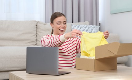Emotional woman unpacking parcel at home. Online store