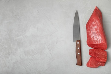 Photo of Flat lay composition with raw meat, knife and space for text on grey background
