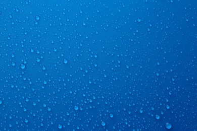 Water drops on blue background, top view