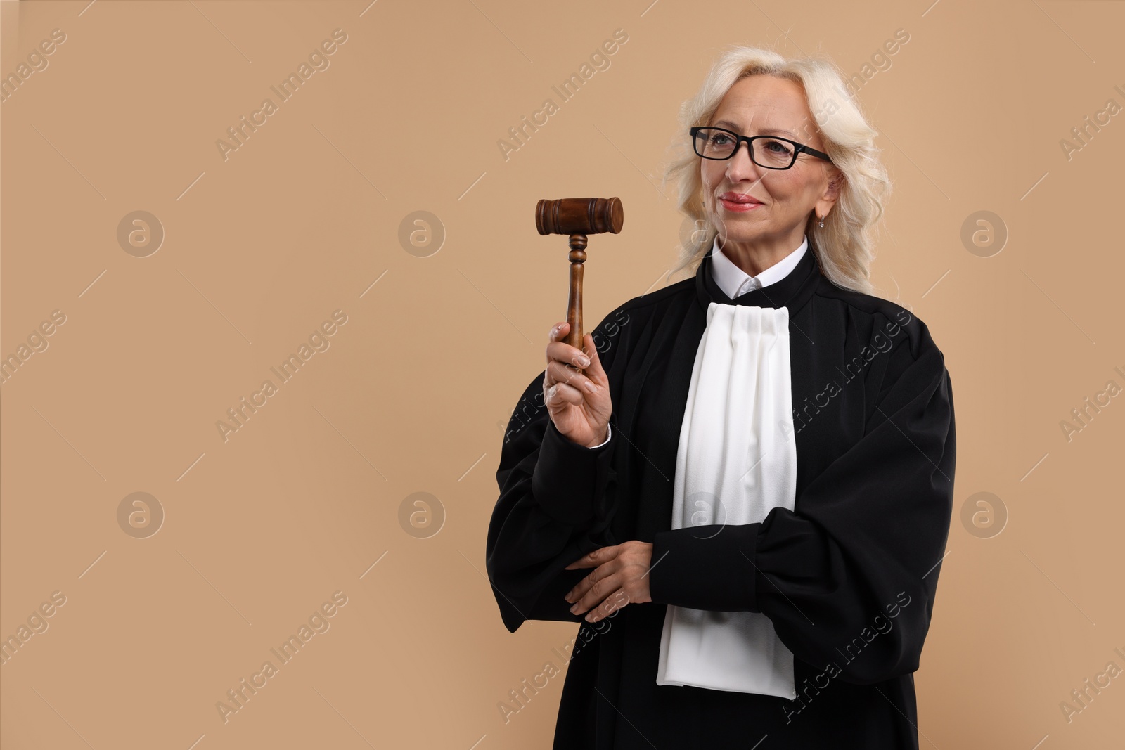 Photo of Senior judge with gavel on light brown background. Space for text