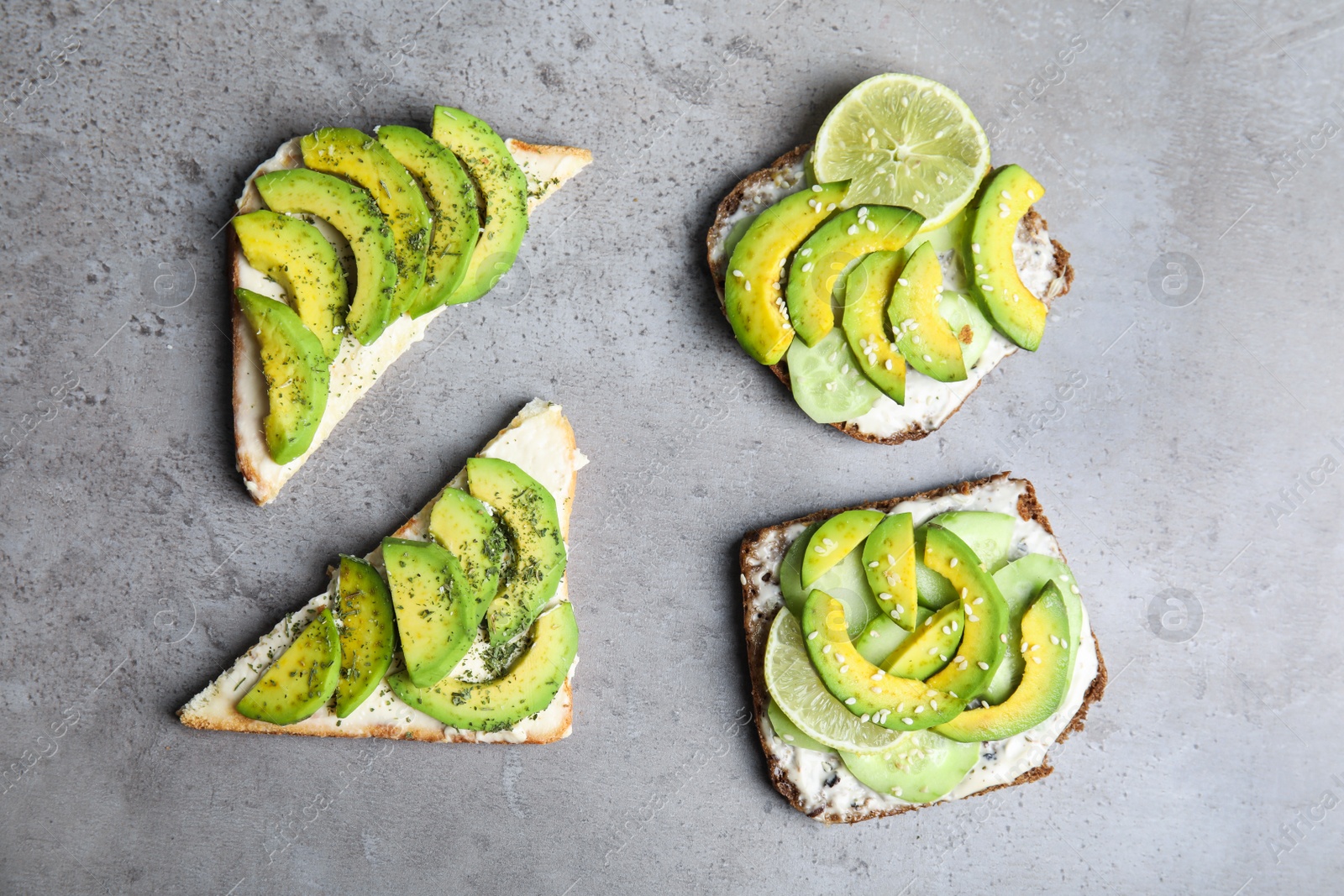 Photo of Tasty toasts with avocado on light grey table, flat lay