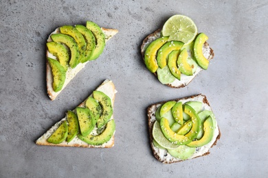 Tasty toasts with avocado on light grey table, flat lay