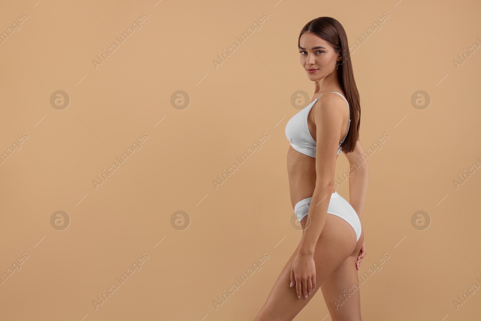 Photo of Young woman in stylish white bikini on beige background. Space for text