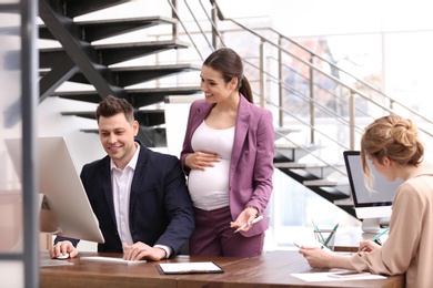 Photo of Young pregnant woman working with her employees in office