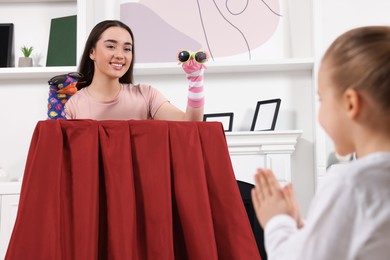 Photo of Happy mother performing puppet show for her daughter at home