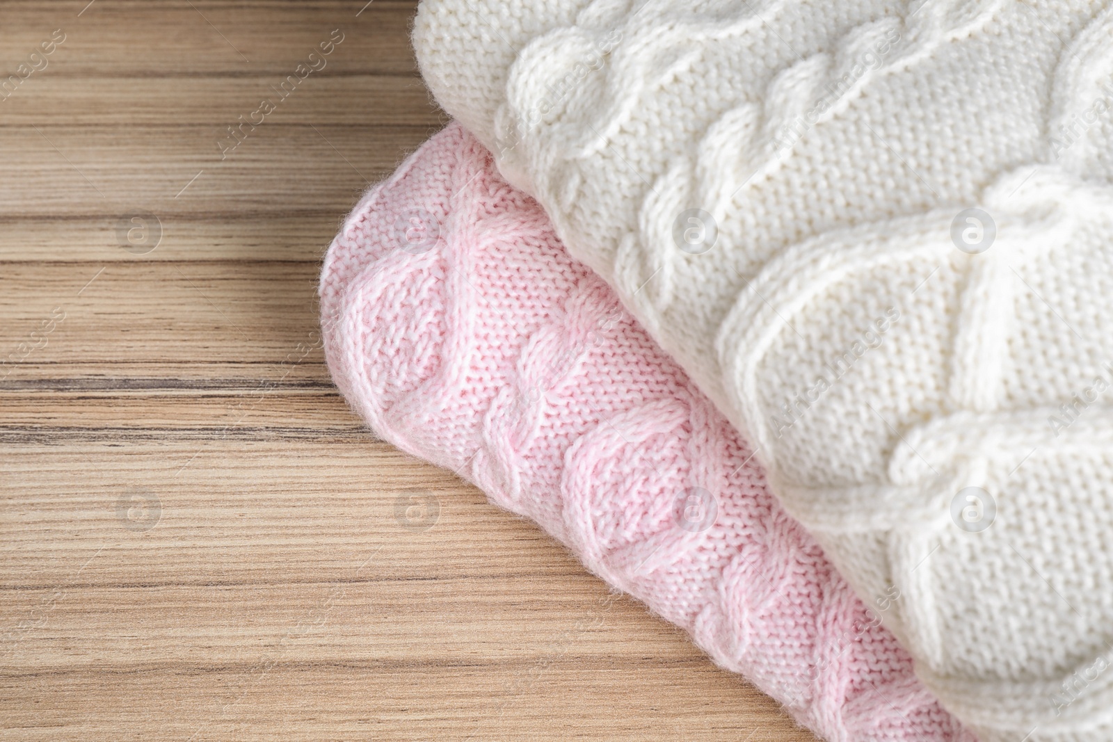 Image of Folded warm sweaters on wooden table, closeup