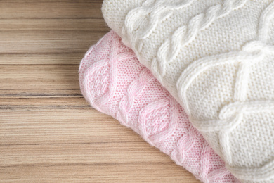 Folded warm sweaters on wooden table, closeup