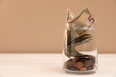 Photo of Donation jar with money on table against color background. Space for text