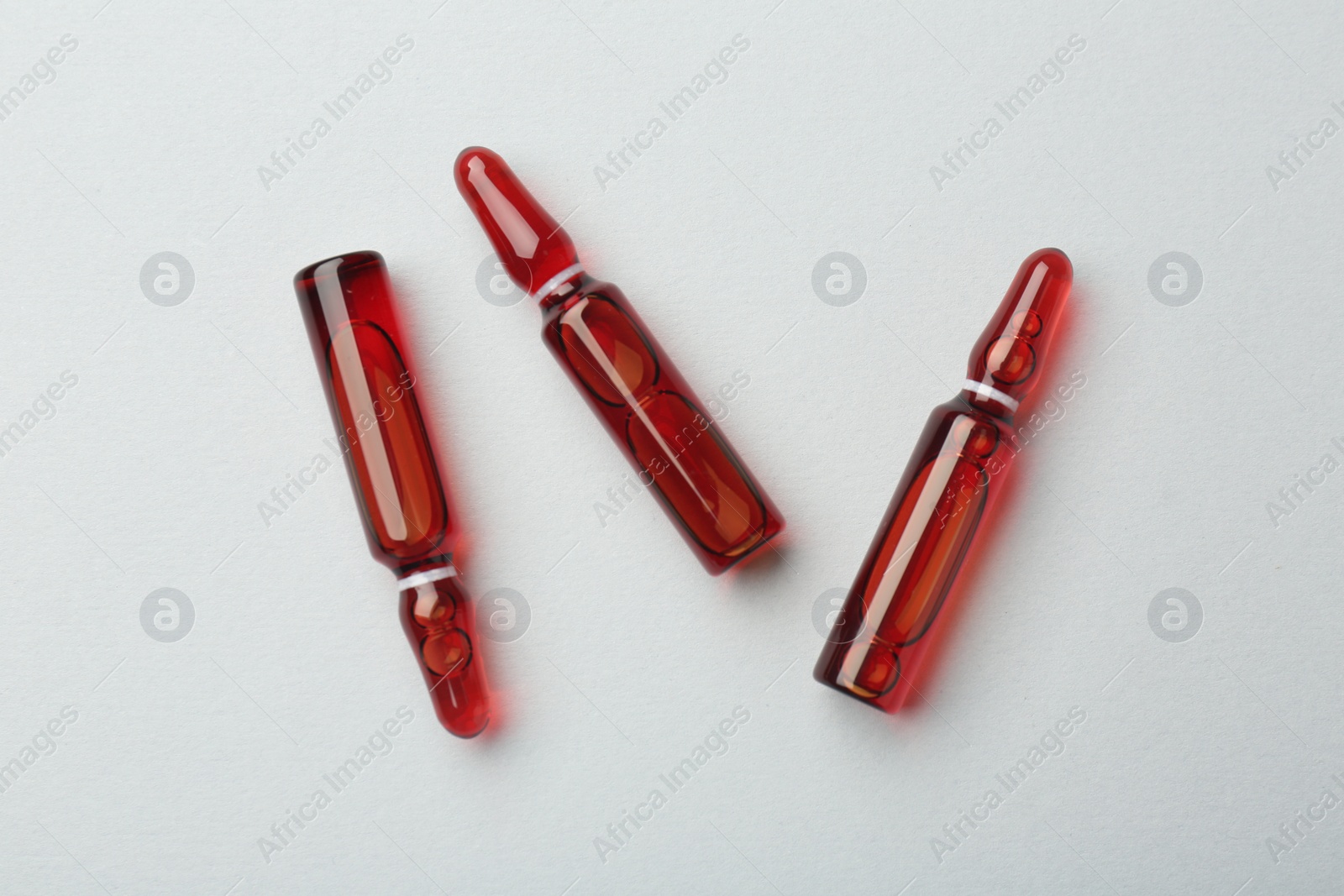 Photo of Glass ampoules with liquid on white background, top view