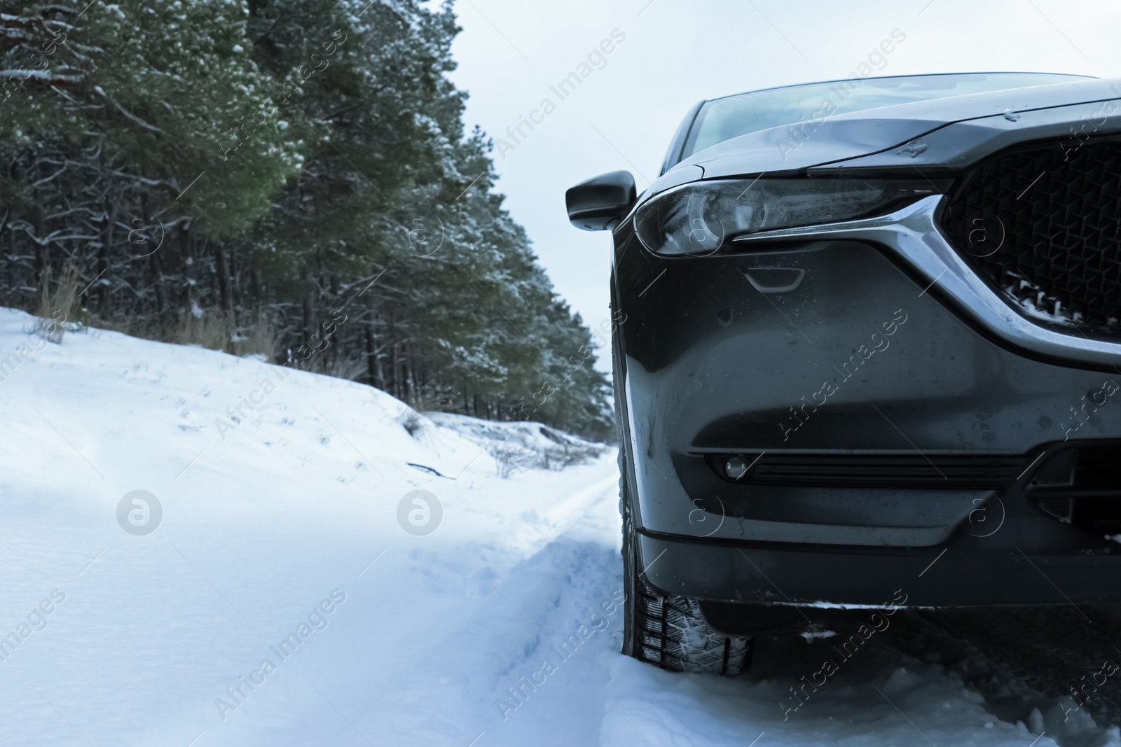 Photo of Snowy country road with car on winter day, closeup. Space for text