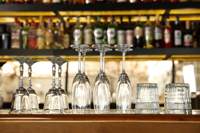 Photo of Different empty clean glasses on counter in bar