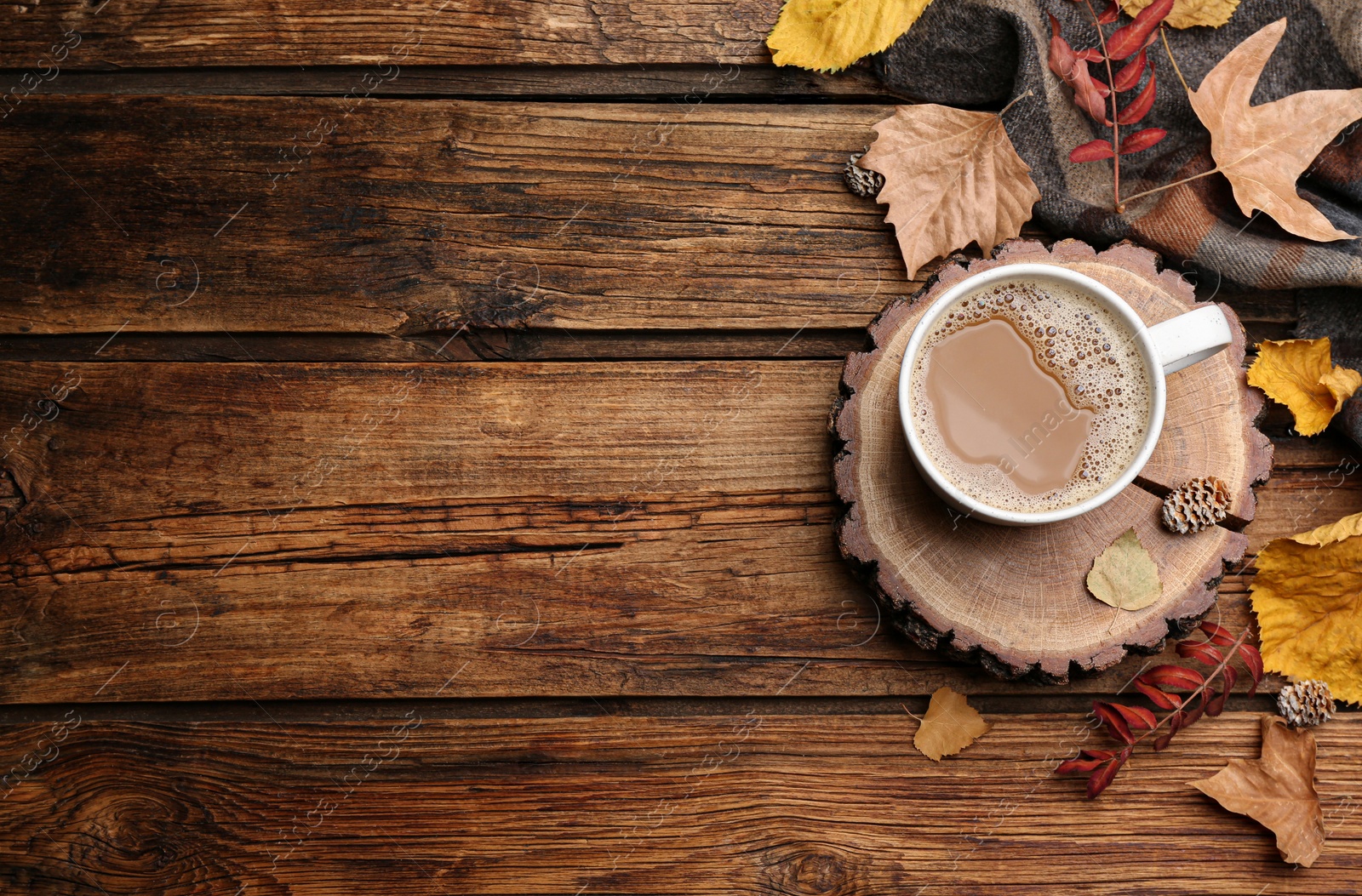 Photo of Flat lay composition with cup of hot drink, plaid and autumn leaves on wooden background, space for text. Cozy atmosphere