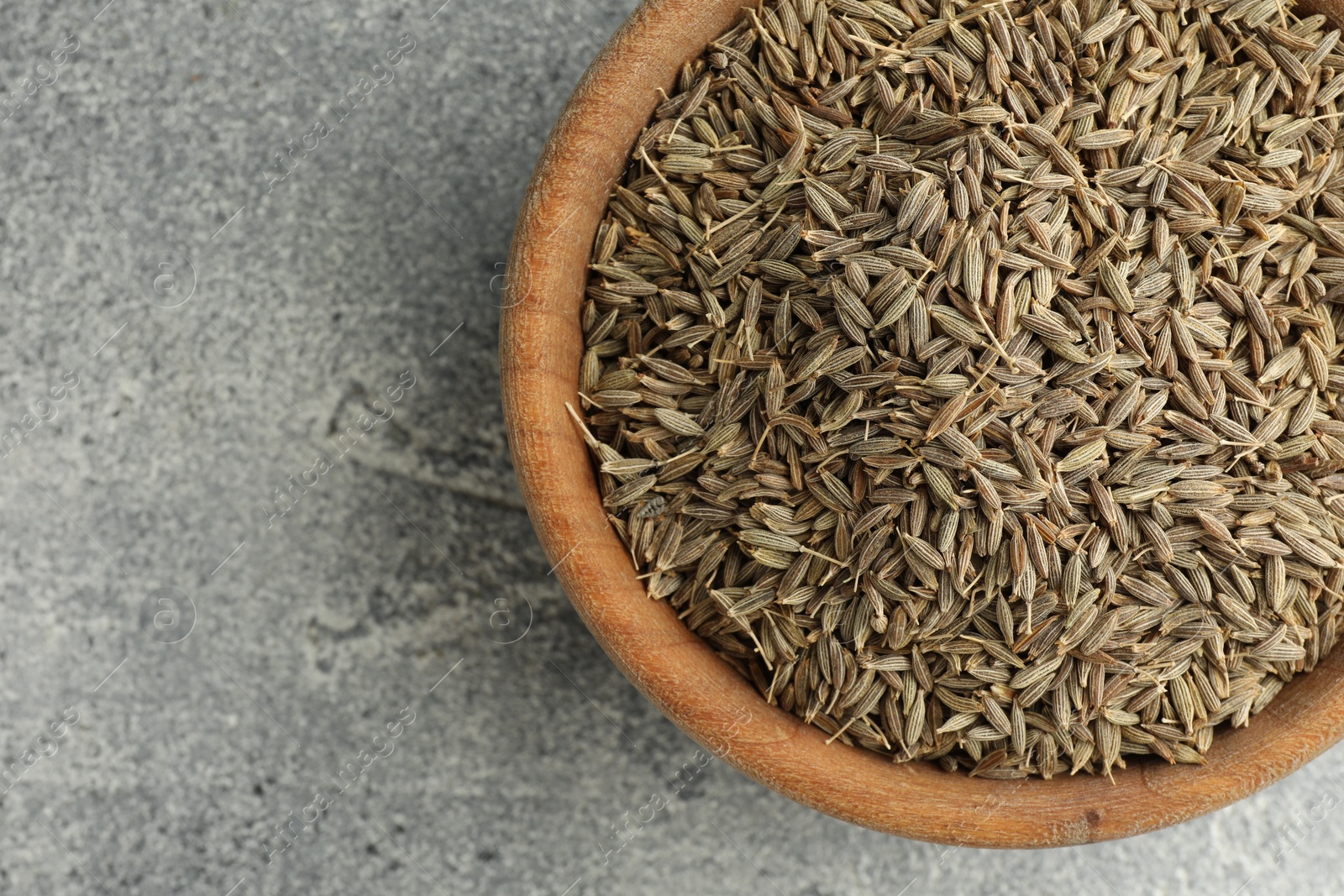 Photo of Bowl of caraway seeds on grey table, top view. Space for text
