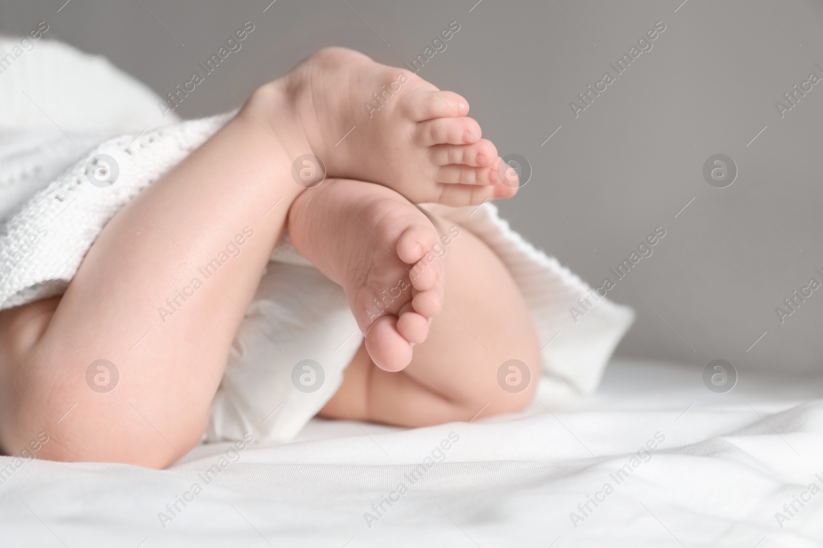 Photo of Little baby with cute feet lying on bed, closeup. Space for text