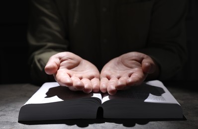 Religion. Christian man praying over Bible at table, closeup