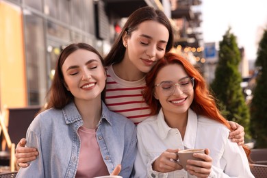 Photo of Happy friends spending time together in outdoor cafe