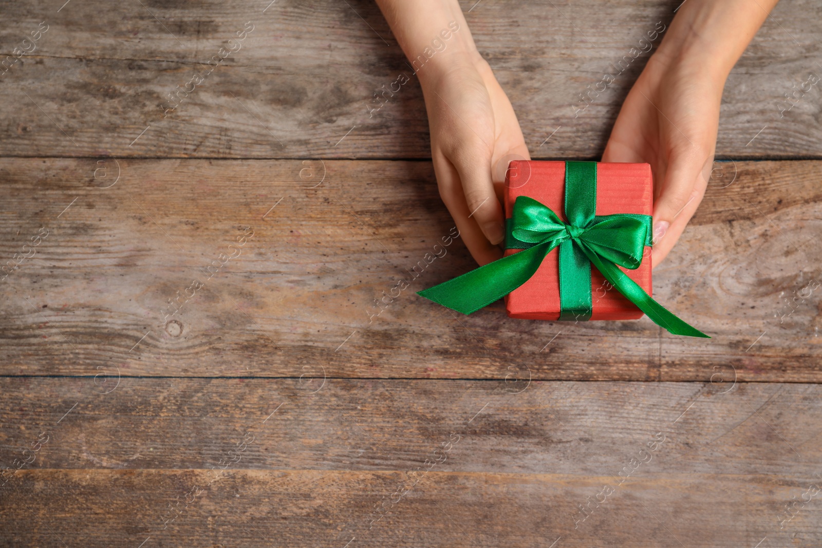 Photo of Woman with beautiful gift box on wooden background, top view