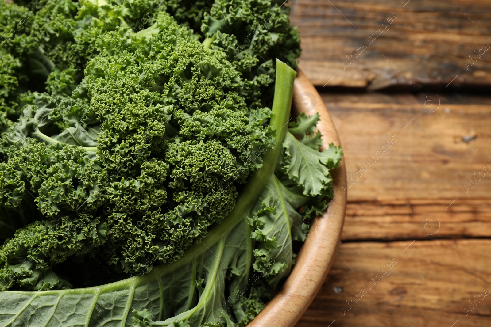 Photo of Fresh kale leaves on wooden table, closeup