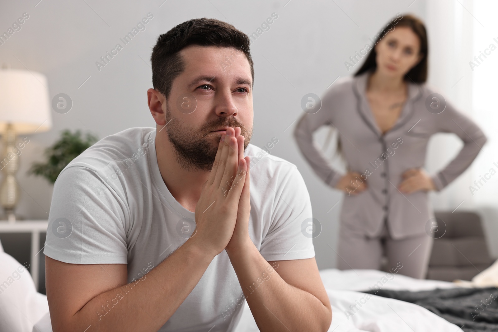 Photo of Offended husband ignoring his wife in bedroom, selective focus. Relationship problems