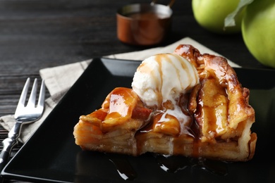 Photo of Slice of traditional apple pie with ice cream served on table, closeup