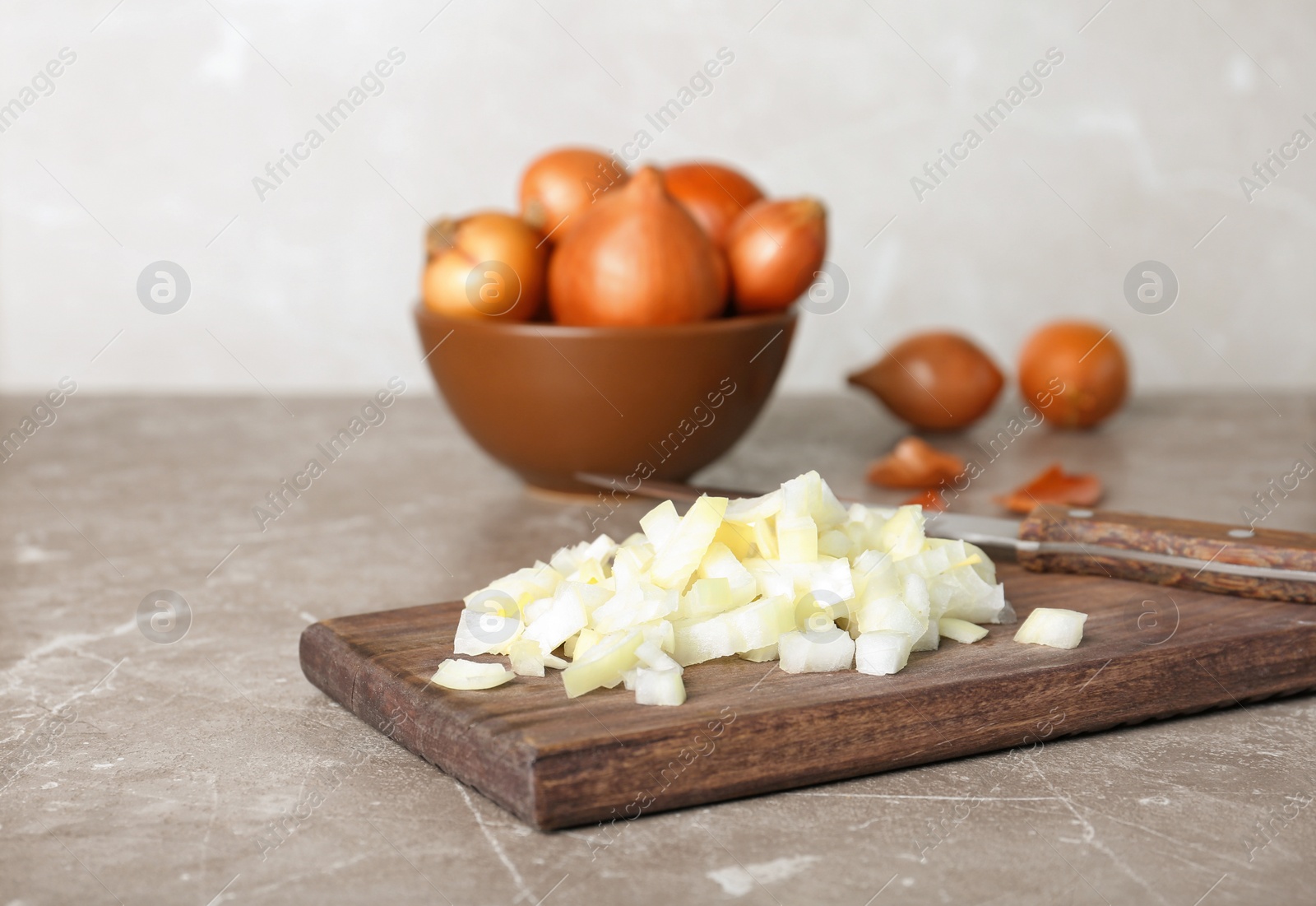 Photo of Wooden board with fresh chopped onion on table