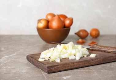 Photo of Wooden board with fresh chopped onion on table