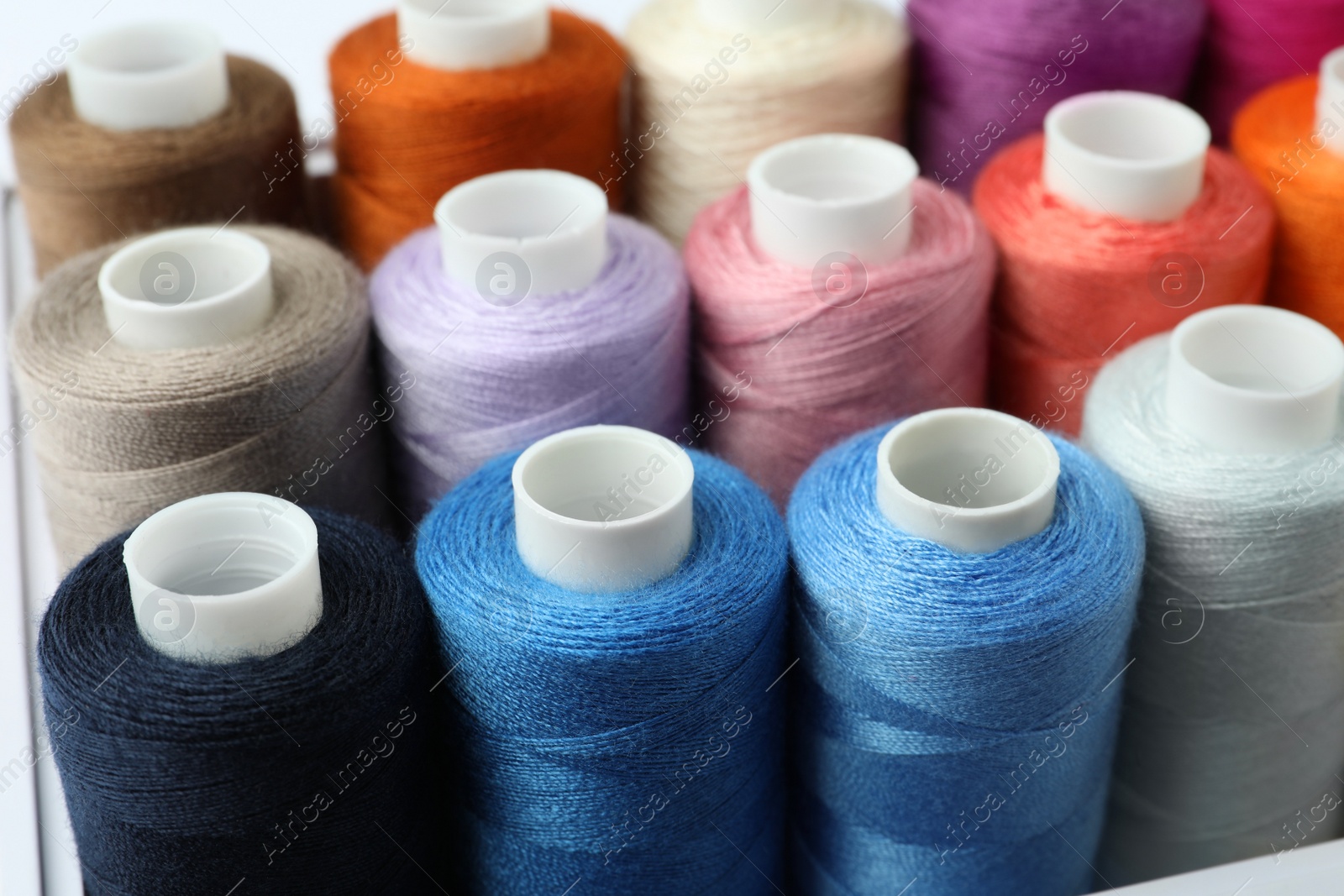 Photo of Different colorful sewing threads in box, closeup