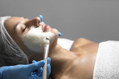 Photo of Cosmetologist applying mask on client's face in spa salon