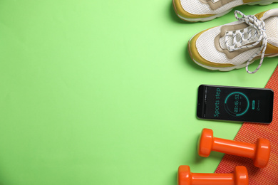 Photo of Flat lay composition with fitness equipment and smartphone on color background, space for text