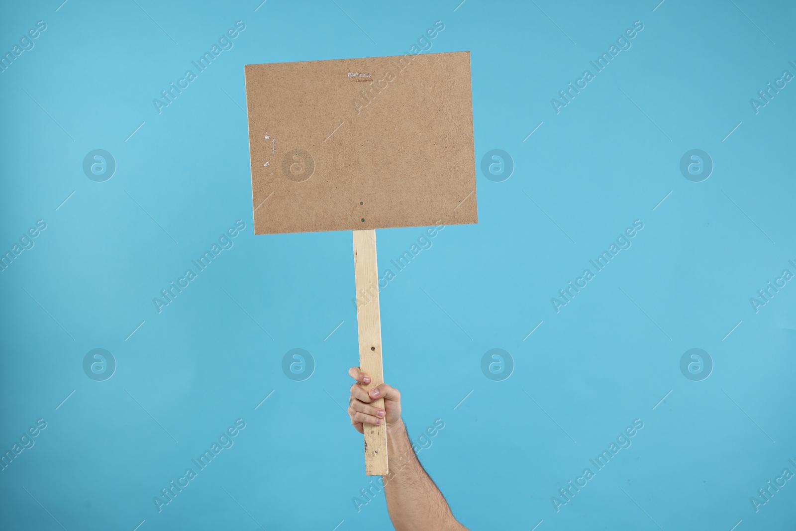 Photo of Man holding blank sign on light blue background, closeup. Space for text