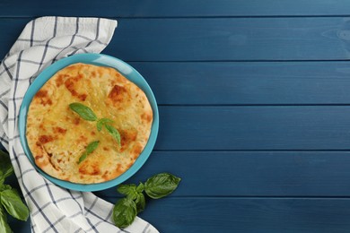 Photo of Delicious khachapuri with cheese and basil on blue wooden table, flat lay. Space for text